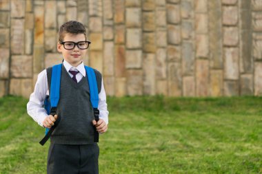 Çim zemin üzerine bir sırt çantası ile öğrenci bardaklarda duruyor