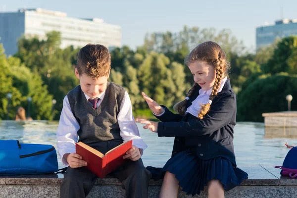 Girl in school clothes distracting a student from reading a book — Stock Photo, Image