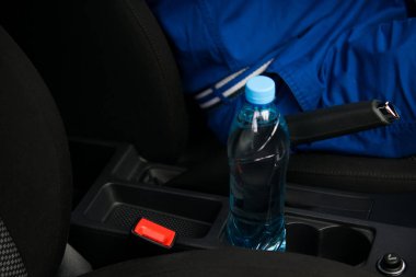 Bir fincan bir arabada orada bir şişe su, sürücü direksiyonda sahibidir