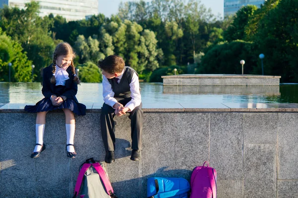 Boy and girl are sitting together in the park after school, speak — Stock Photo, Image