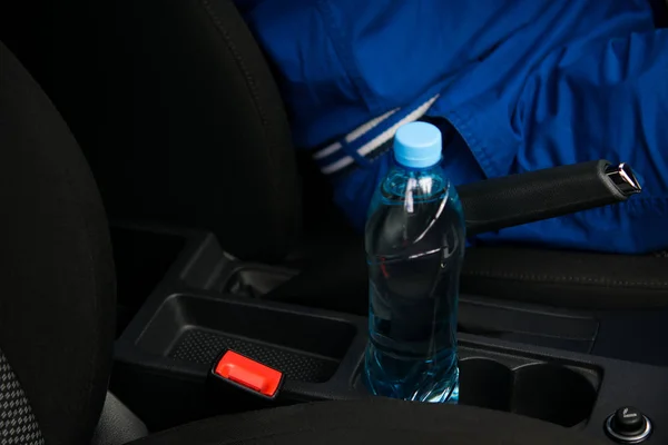 В машине в держателе для чашки есть бутылка воды, для водителя за рулем — стоковое фото