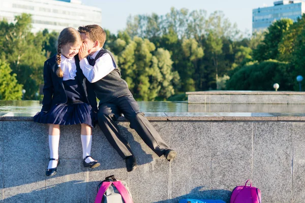 Chlapec vypráví dívky tajemství ze školy, dětí v oblečení pro školy — Stock fotografie