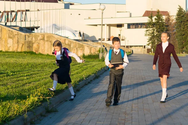 Три студента гуляют по парку с портфолио после занятий — стоковое фото