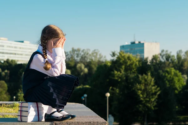 Liten skolflicka sitter på en lärobok och gråter, vill inte studera — Stockfoto