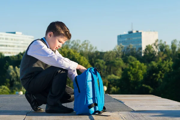 Мальчик в школьной одежде собирает сумку для школы — стоковое фото