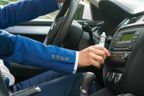 Empresário com cigarro eletrônico muda a música no carro na viagem — Fotografia de Stock