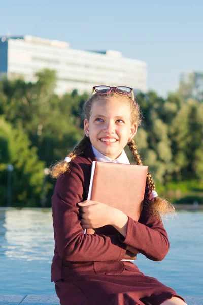 Девушка в школьной форме держит папку для школы — стоковое фото