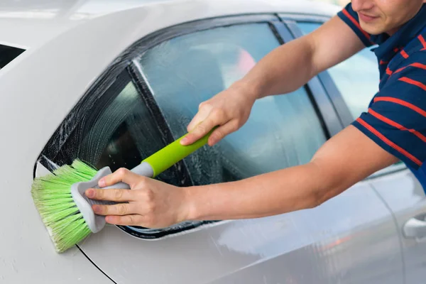 Bílé auto, mytí zeleným štětcem, s pěnou — Stock fotografie