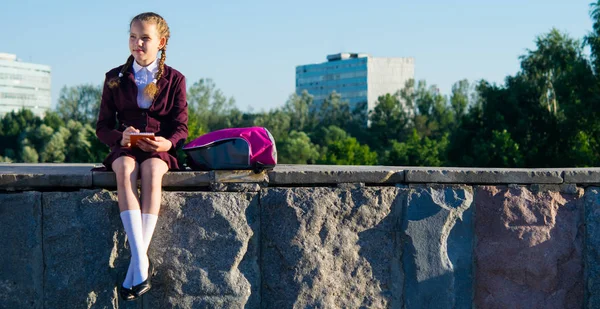 Dívka sedí a zapisování poznámek po škole, venku — Stock fotografie