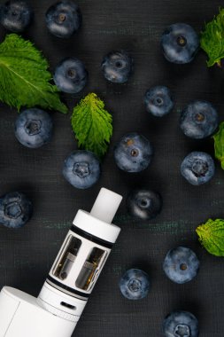 Yaban mersini ve nane bir siyah arka plan üzerine beyaz bir elektronik sigara çevrilidir