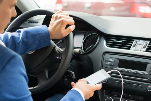 Водитель за рулем автомобиля включает музыку с телефона — стоковое фото