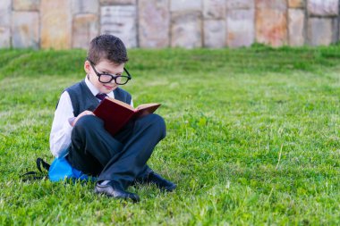 Çocuk okuldan, kitapta, park açık havada okuma Çimenlikte oturan sonra gözlük