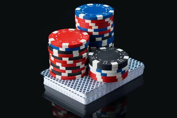 Висока ставка червоних фішок на палубі ігрових карток, на чорному столі з відображенням — стокове фото
