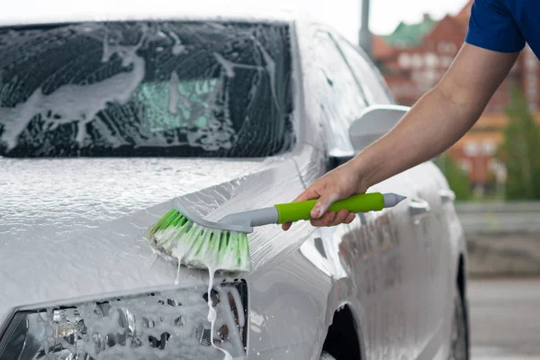 Beyaz bir araba bir temizlik işçisi, yeşil bir fırça ile el tarafından yıkanmış