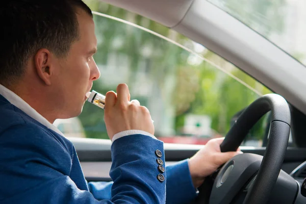 Muž v autě kouří elektronické cigarety — Stock fotografie