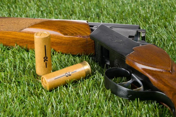 Rifle de caza y dos cartuchos en un césped verde — Foto de Stock
