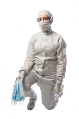 holding tıbbi maskesi oturan koruyucu kıyafetli kız