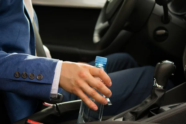 Homem ao volante de um carro, pegou uma garrafa de água na estrada — Fotografia de Stock