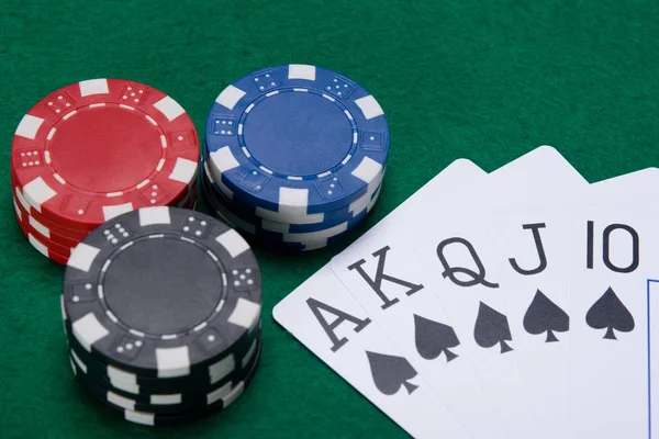 Un jeu de cartes avec un costume noir, et un gros pari sur une table verte — Photo