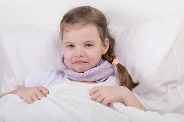 Kleines Mädchen hat Halsschmerzen, sie wärmt ihn im Bett liegend — Stockfoto