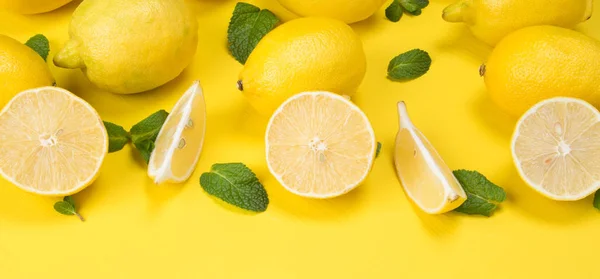 Limoni tagliati a fette e sdraiati insieme alla menta su fondo giallo — Foto Stock