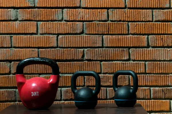 Üç ağır dumbbells bir tuğla duvar, çapraz-sığması için bir arka plan olarak stand