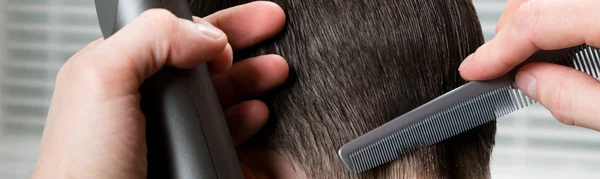 stylist on hairstyles, shaves the electric machine with the occipital zone, combing the boy