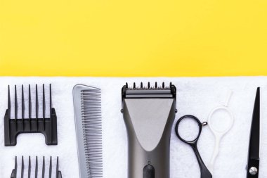 Beyaz havlu setinde saç kesme aletleri, Sarı zemin üzerine kavramı