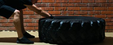 CrossFit işgal ile bir otomobil lastiği, karşı bir tuğla duvar arka plan