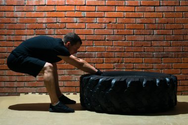 Kauçuk lastik üzerinde tuğla kırmızı arka plan ile atlet crossfit eğitim