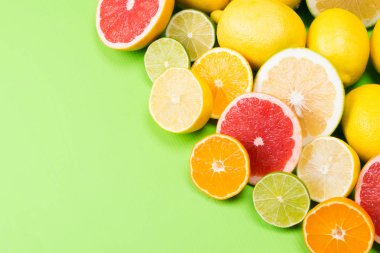 farklı dilim limon meyve, mandalina ve greyfurt birlikte bir köşede, yeşil bir arka plan üzerinde yalan.