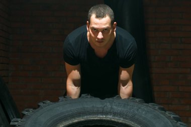 adam arabanın lastik tekerlek ile bir salonda spor devreye girer