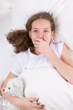 kız yatakta esner ve bir oyuncak kutup ayısı sarılarak