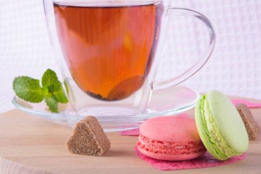 bir fincan nane çayı ile ahşap tahta ve şeker bir kalp gibi iki aşçı macaron