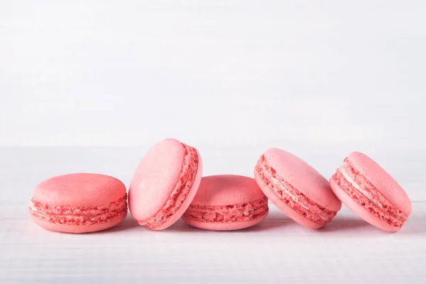 delicious pink row of dessert macaron, on a wooden background