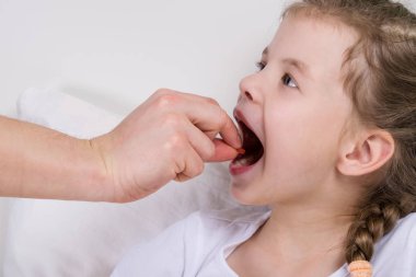 Doktor hap geniş ağzını açtı küçük kızın ağzına koyar.