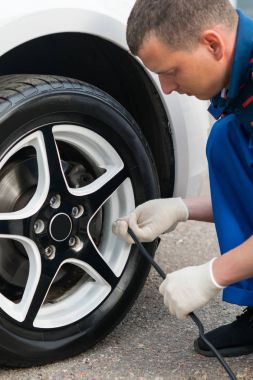 adam pompalar arabada, bir tekerlek gözlemler bir norm baskı lastikleri