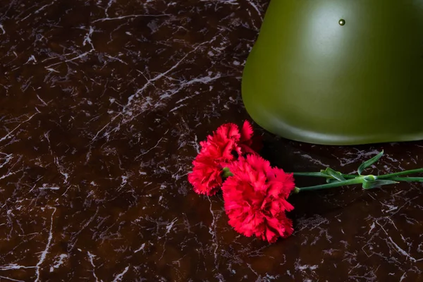 military helmet and carnations, against the background of the monument
