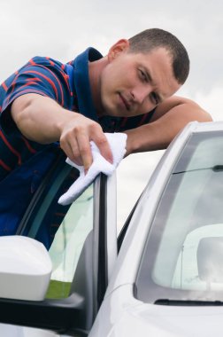 adam üst kısmındaki arabanın kapısını bir bez ile silinerek yakın çekim