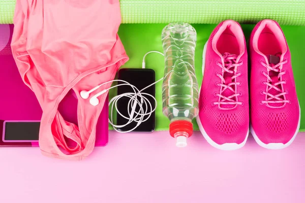 female pink set of things and accessories for playing sports lies on a green mat