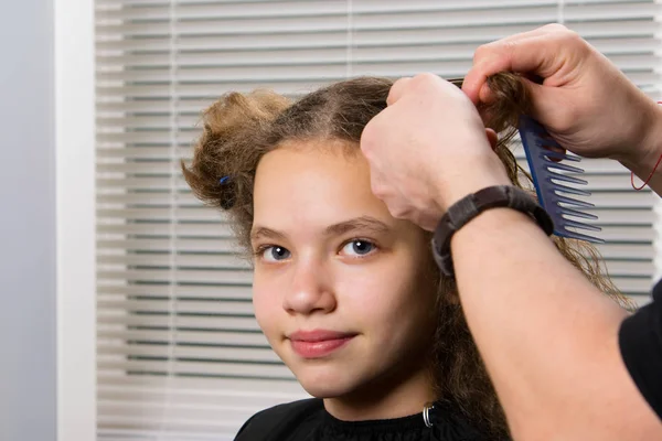 the hairdresser does a hairstyle for a girl, with curly hair