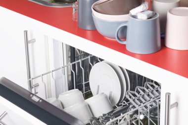 Temiz bardaklar ve tabaklar bulaşık makinesinin içinde durduğu masanın üzerinde.