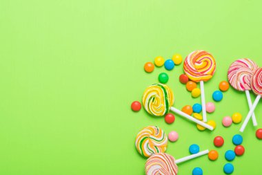 Çubukta karamel ve yeşil arka planda renkli jelibon.