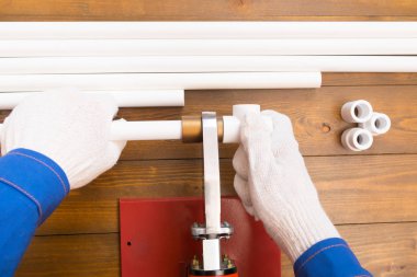 Koyu renk ahşap arka planda, beyaz eldivenli bir işçi, kesim malzemeleri için mavi makas tutuyor, bir yer var.