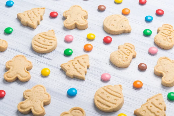 on a light gray background, cookies in the form of a Christmas tree, a snowman, Santa Claus and colorful dragees
