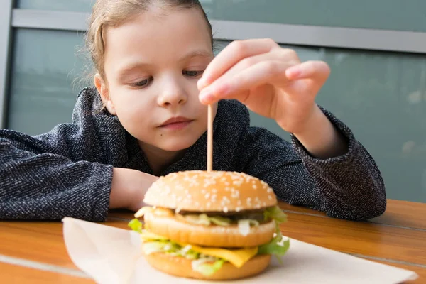 Teen Girl Tira Fuori Bastone Legno Hamburger Mentre Seduto Tavolo — Foto Stock