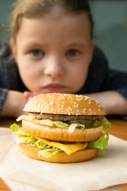 Kız uzaktan büyük lezzetli bir hamburgerciye bakıyor.