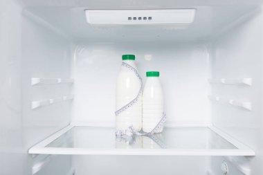 Buzdolabının arka planındaki vücut büyüklüğünü ölçmek için konsept süt ve metre, süt diyeti