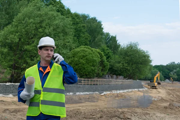 a worker in a special suit calls up with the customer about the stages of construction