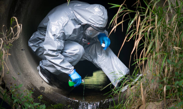 close-up, the terrorist in a protective suit and gloves, pours liquid with poison, for infection, in a drainpipe